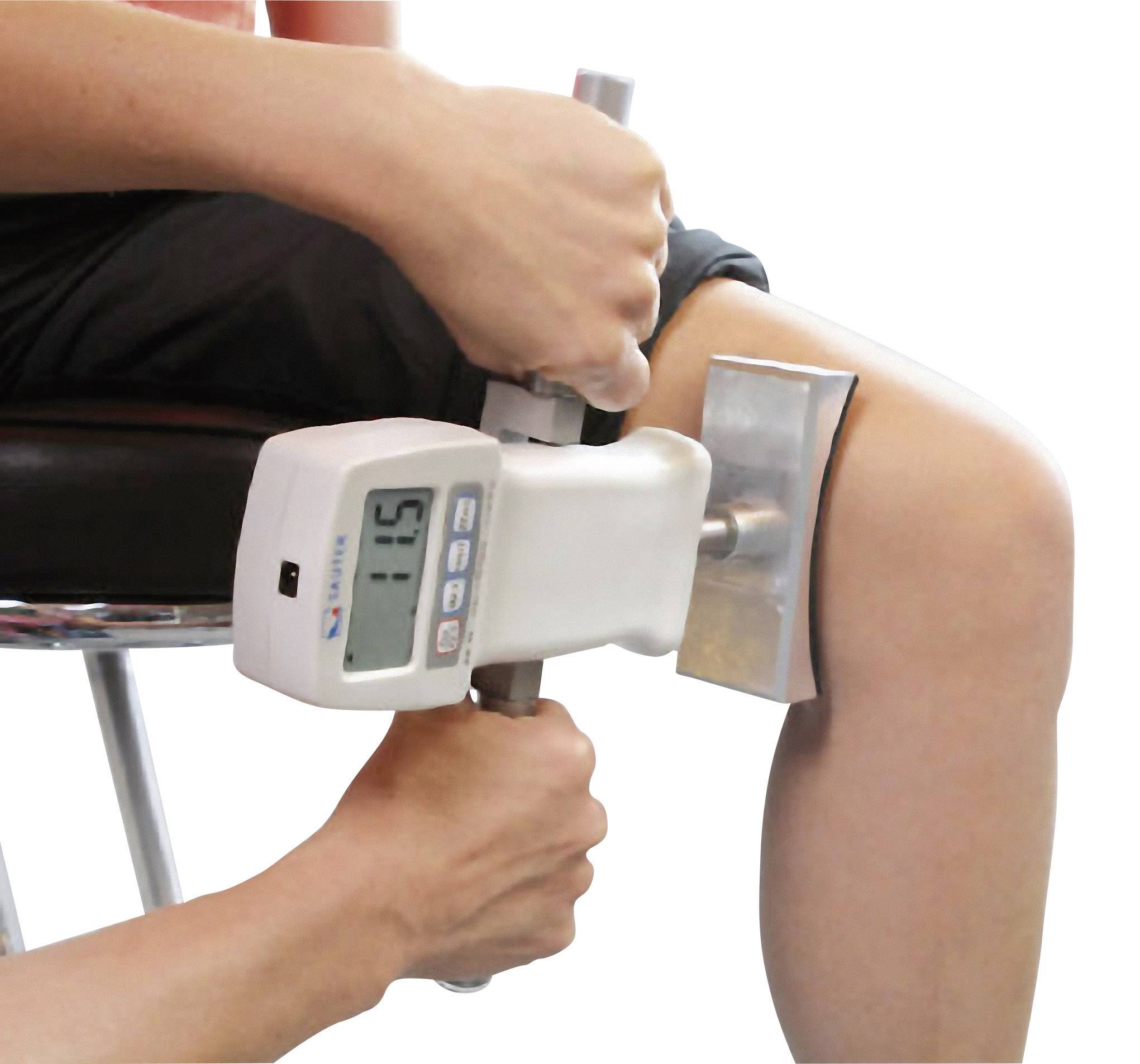 A person is measuring the knee extension force using a medical device. The device displays '15' on a digital display.