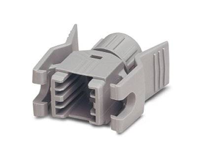 Grey plastic plug with four lateral slots and ribbed grip areas, used for connecting cables.