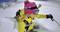 A person in a yellow jacket is skiing down a mountain through deep snow. They are wearing a pink hat and ski goggles.