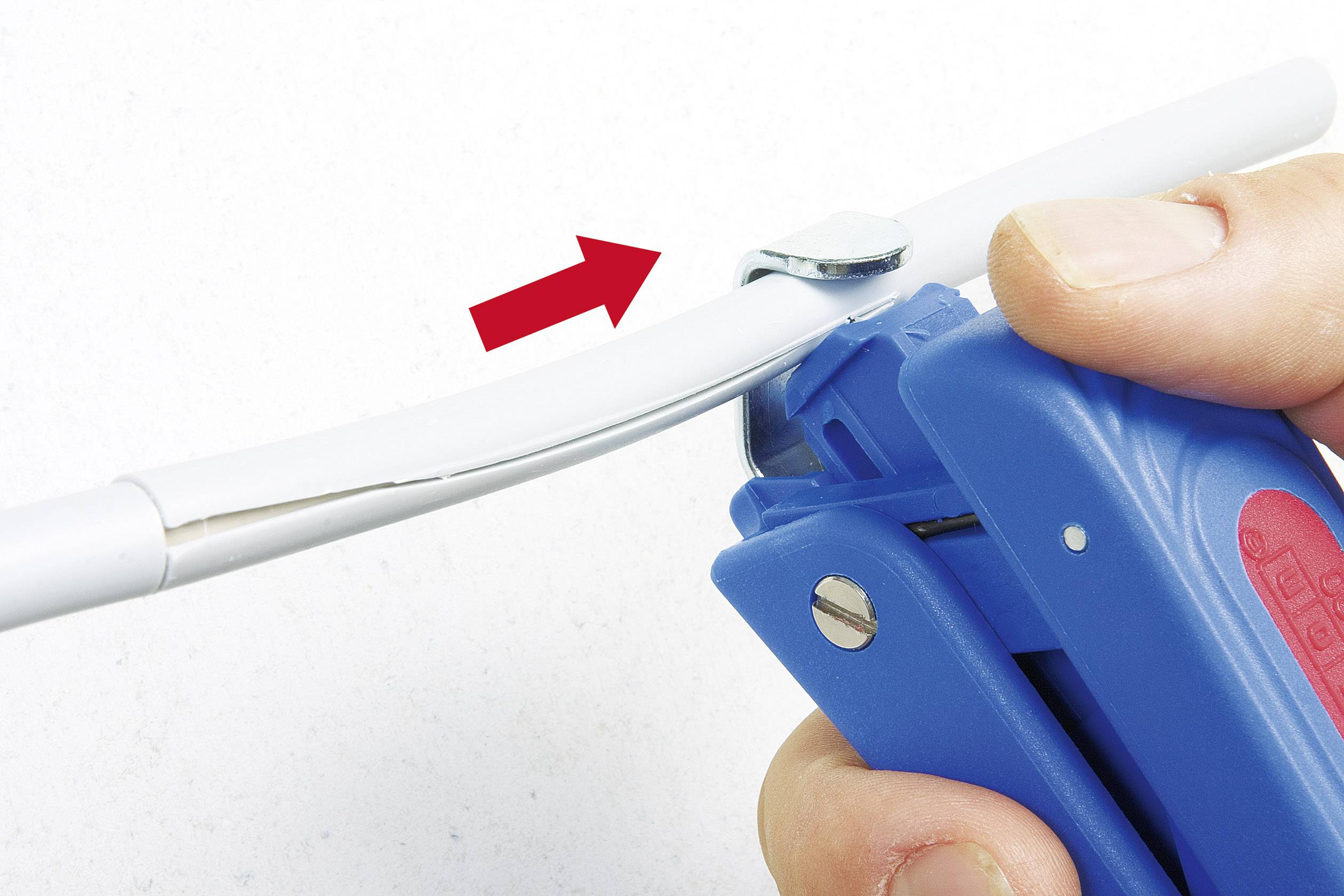 Close-up of a blue cable cutter cutting through a white cable. A red arrow indicates the cutting point.