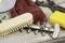 Cleaning implements on a table: A wooden brush, a rust-coloured cloth, a yellow sponge and pruning shears are visible.