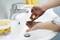 A person is washing dirty hands with a specialised hand cleanser at a sink. Water is flowing from the tap.