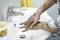 A person is cleaning dirty hands over a sink with special hand-cleaning cream from a container beside the tap.