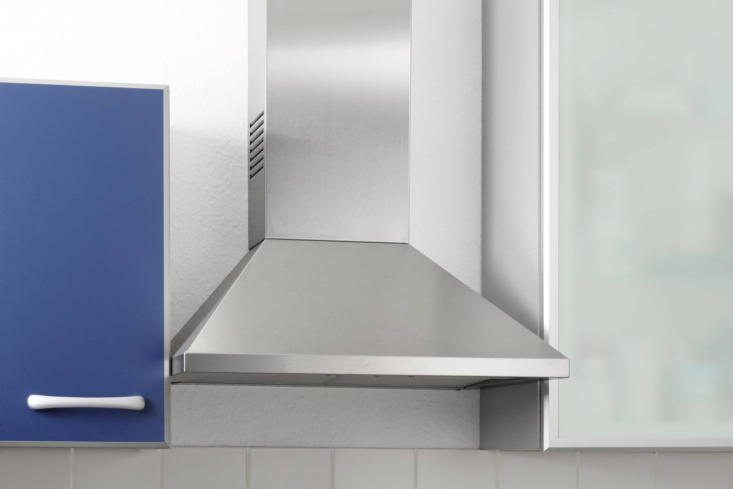 A modern stainless steel cooker hood in a kitchen between two cupboards.
