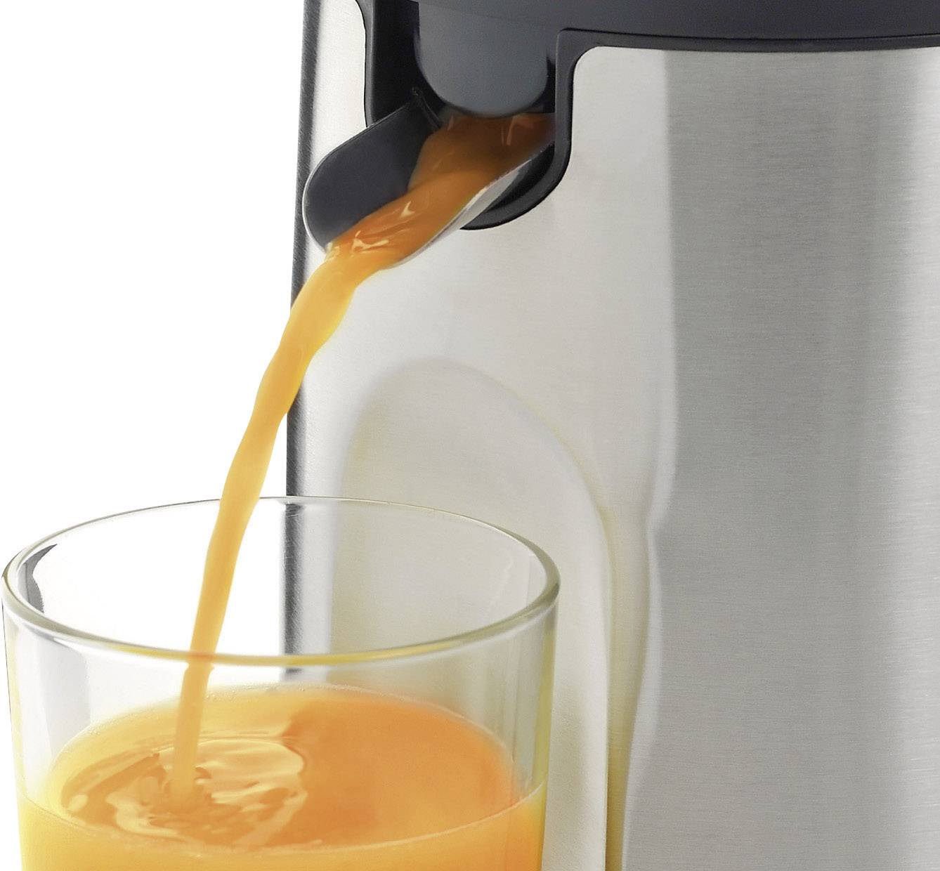 A silver juicer is pouring fresh orange juice into a glass. The juice flows from the black spout into the half-filled glass.