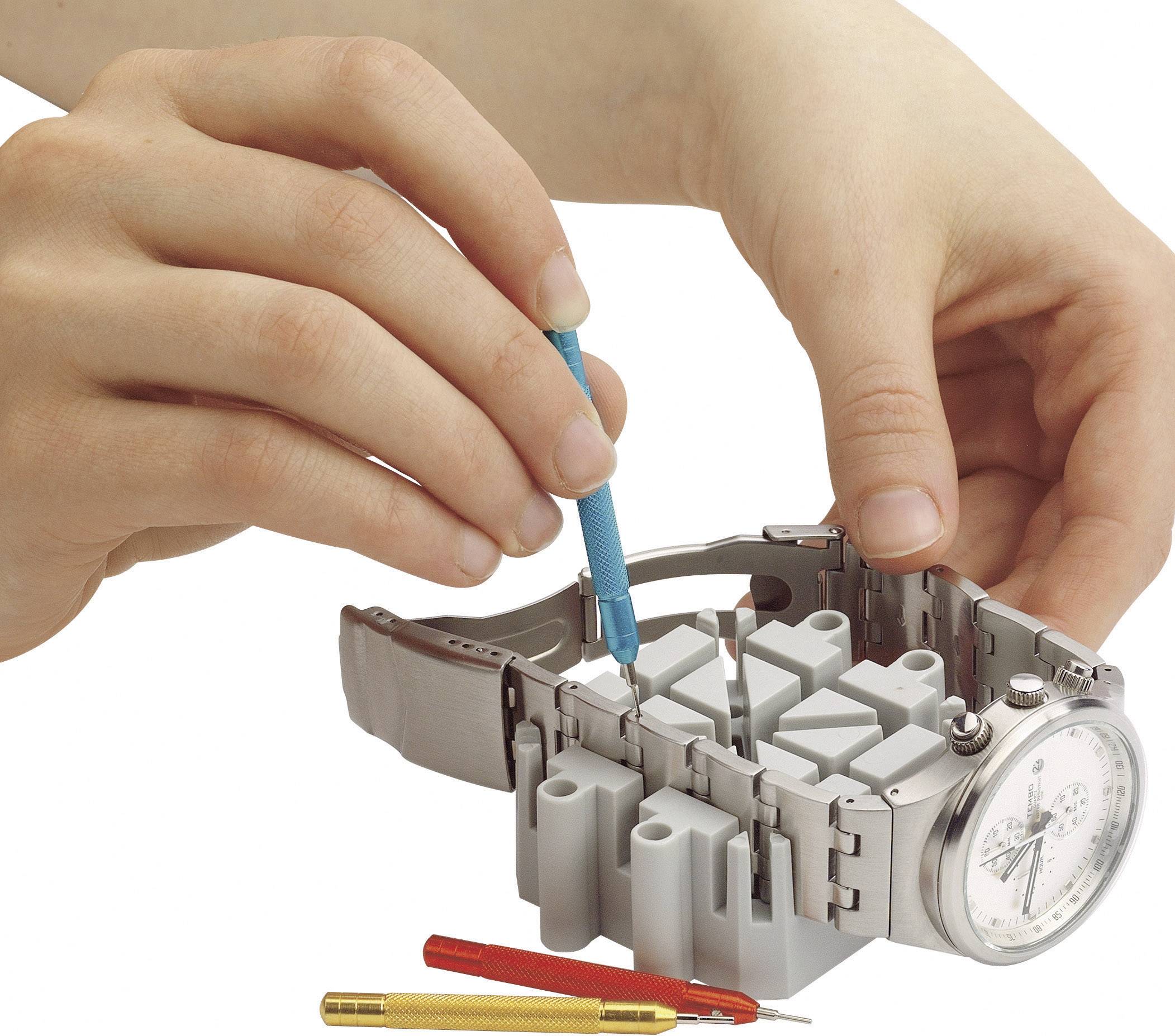 Hands are opening a watch bracelet with a blue tool on a watch holder.