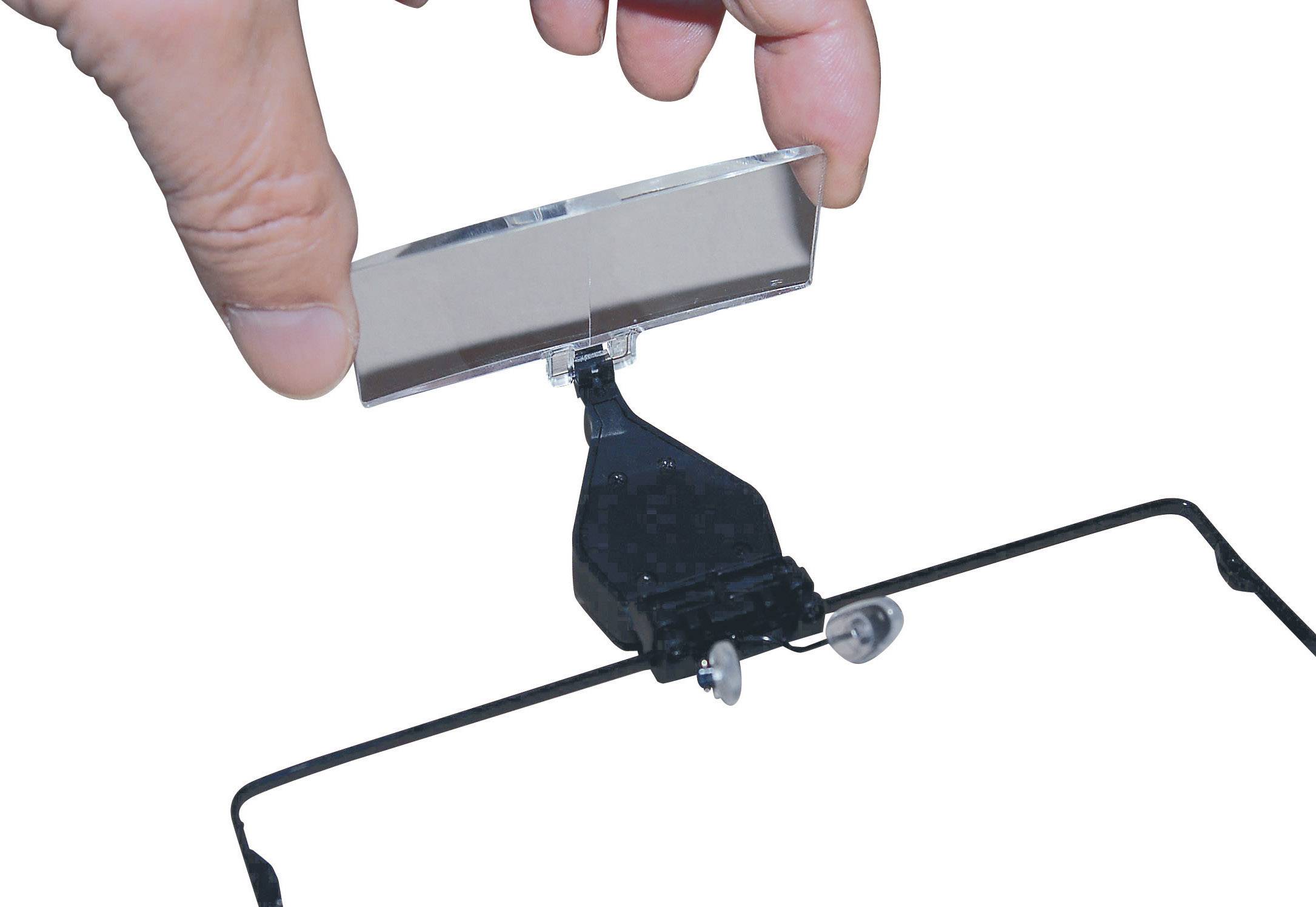 'A hand holds a small mirroring device attached to a pair of glasses. It is used for reflecting light or for optical purposes.'