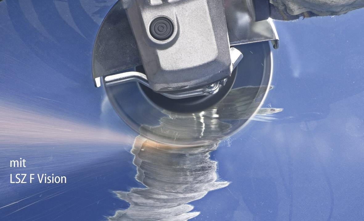 An angle grinder is grinding a metallic surface. Sparks are flying from the point of contact. Bottom left reads 'with LSZ F Vision'.