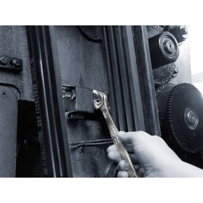 A hand uses a spanner to tighten a screw on a large, industrial machine.