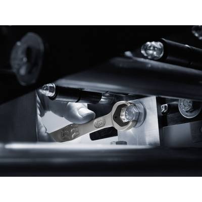 Close-up of a spanner tightening a screw in a machine. A hand is holding the spanner in a workshop environment.