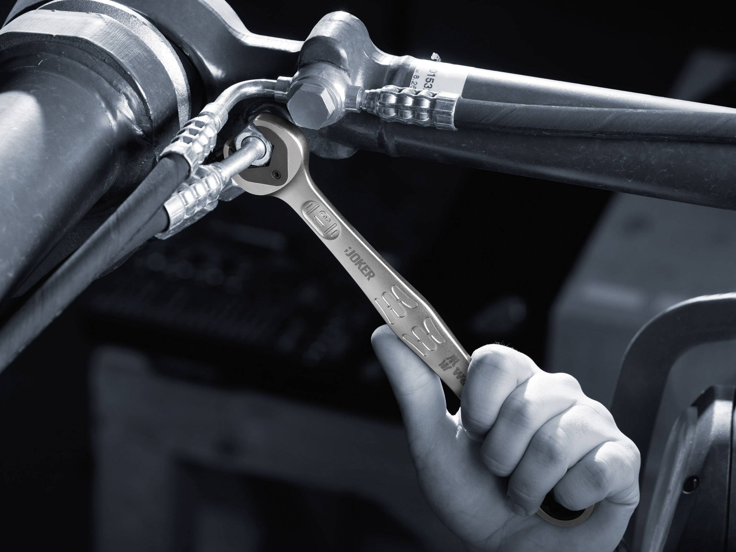 A hand is using a spanner to tighten screwed pipes.