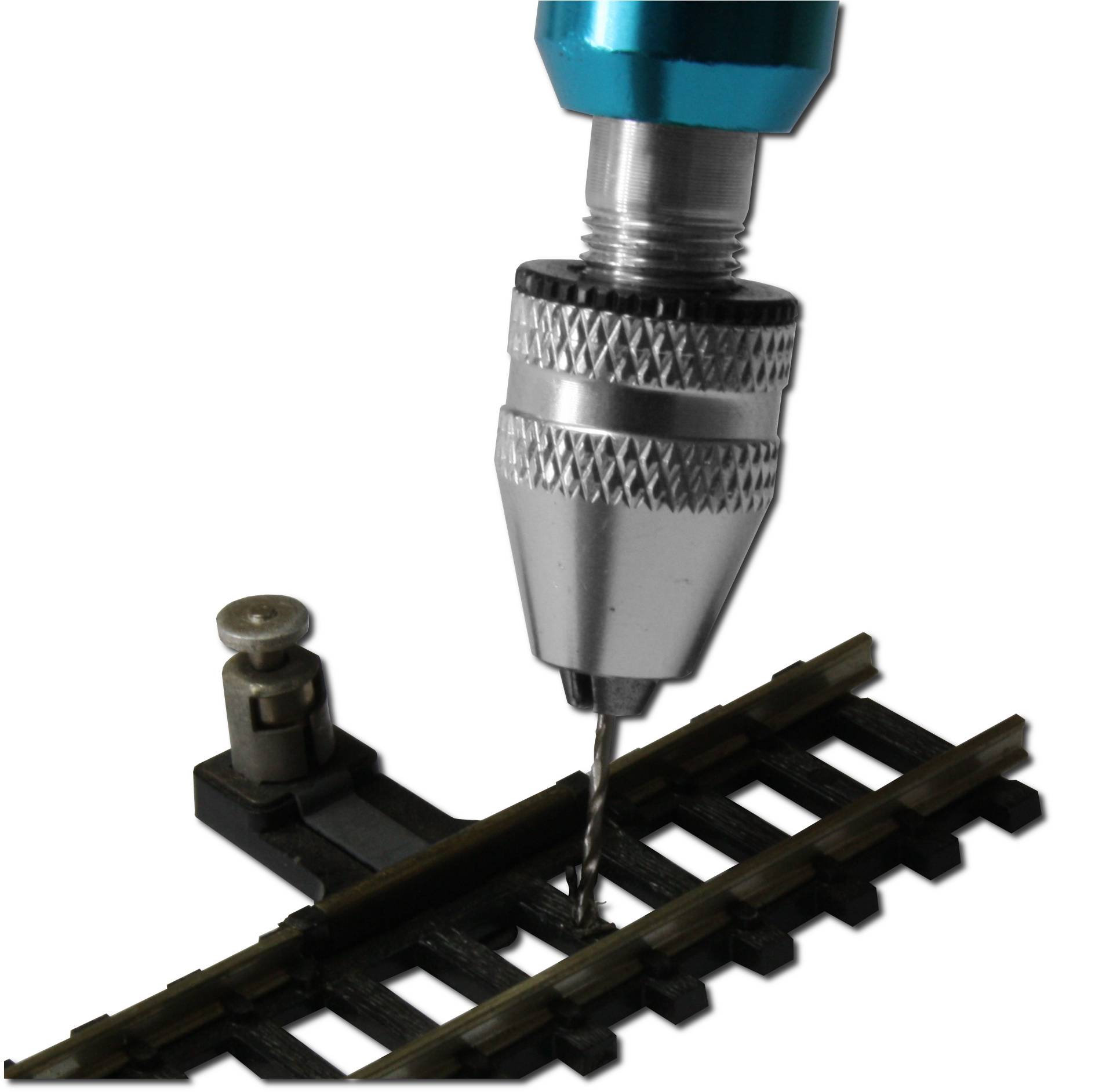 A silver drill with a blue handle is drilling a hole in a model railway track.