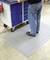 A person is standing on a grey, non-slip mat in front of a blue tool trolley. This scenario depicts a workshop environment.