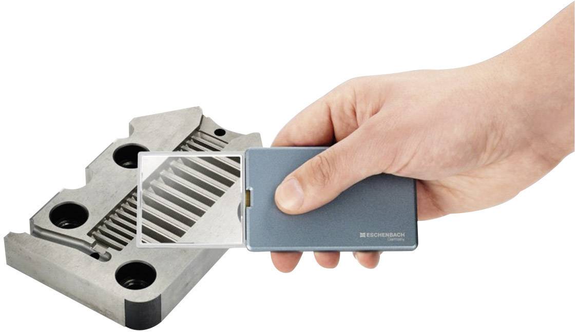 A hand holds a digital measuring instrument over a metallic machine part with parallel grooves to inspect the surface.
