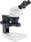 A white microscope with two eyepieces, a black stand and control elements at the front, for scientific investigations.