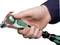 A hand grips a ratchet spanner and turns the green wheel to change direction. The handle is black and green.