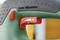 Close-up of a green tool with a red switch, labelled 'Low Vibration' and a dial with minus and plus symbols for adjusting vibration intensity.