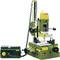 Green milling machine on a table, with a yellow headpiece. Beside it, a black electronic control unit.