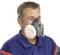 A person is wearing a respiratory protective mask in grey and white, indicating workplace safety.