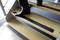 A person is walking down a staircase with non-slip strips on the steps.