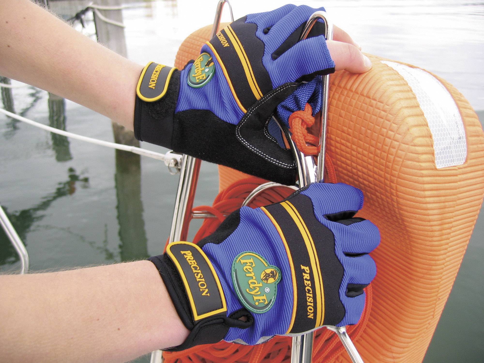 Hands in blue gloves grasp a rope attached to an orange buoy, presumably during a boat trip on the water.