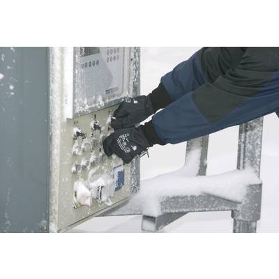 A person wearing gloves operates a snow-covered control panel outdoors.