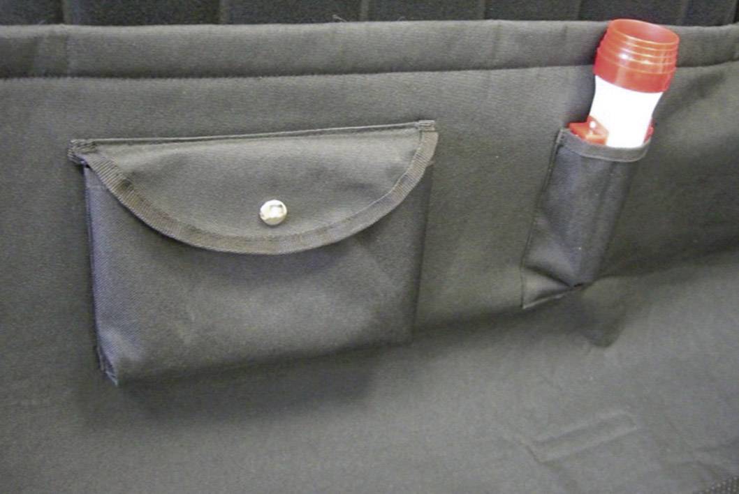 A black fabric bag and a case with a red torch are attached to a black wall.