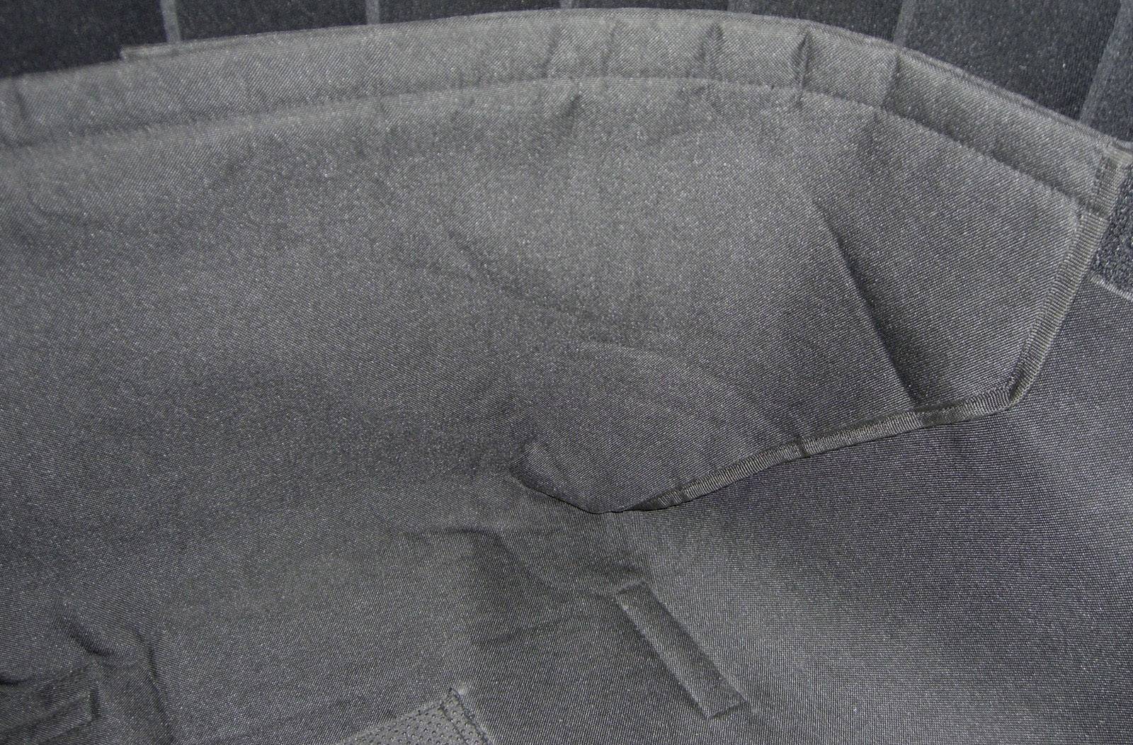 Interior view of an empty black fabric bag with sewn details and multiple compartments.