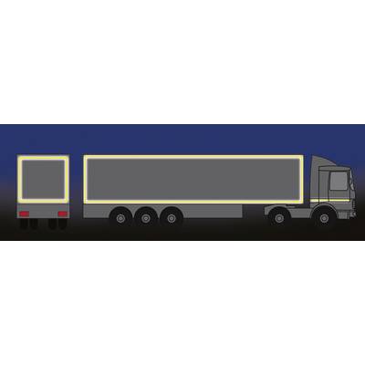 Lorry with trailer at night; reflective strips on side and rear edges stand out brightly against the dark background.