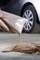 A hand is pouring sand from a bag onto the ground next to a car tyre, potentially to stabilise a slippery surface.