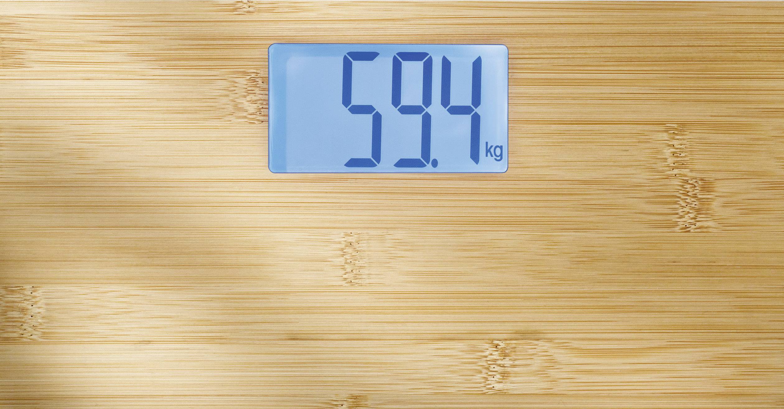 Digital scales on a wooden surface displaying '59.4 kg'.