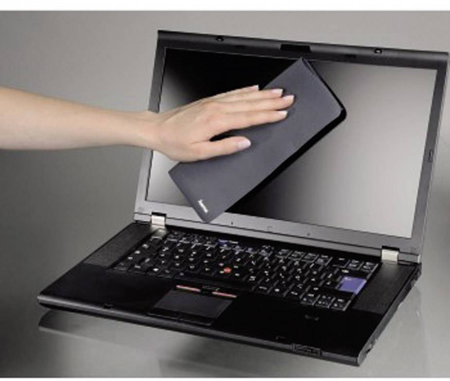 A hand wipes a cloth across a laptop screen to clean it.