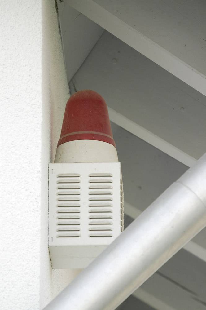 Red warning light on a building wall to alert of hazards or intruders.