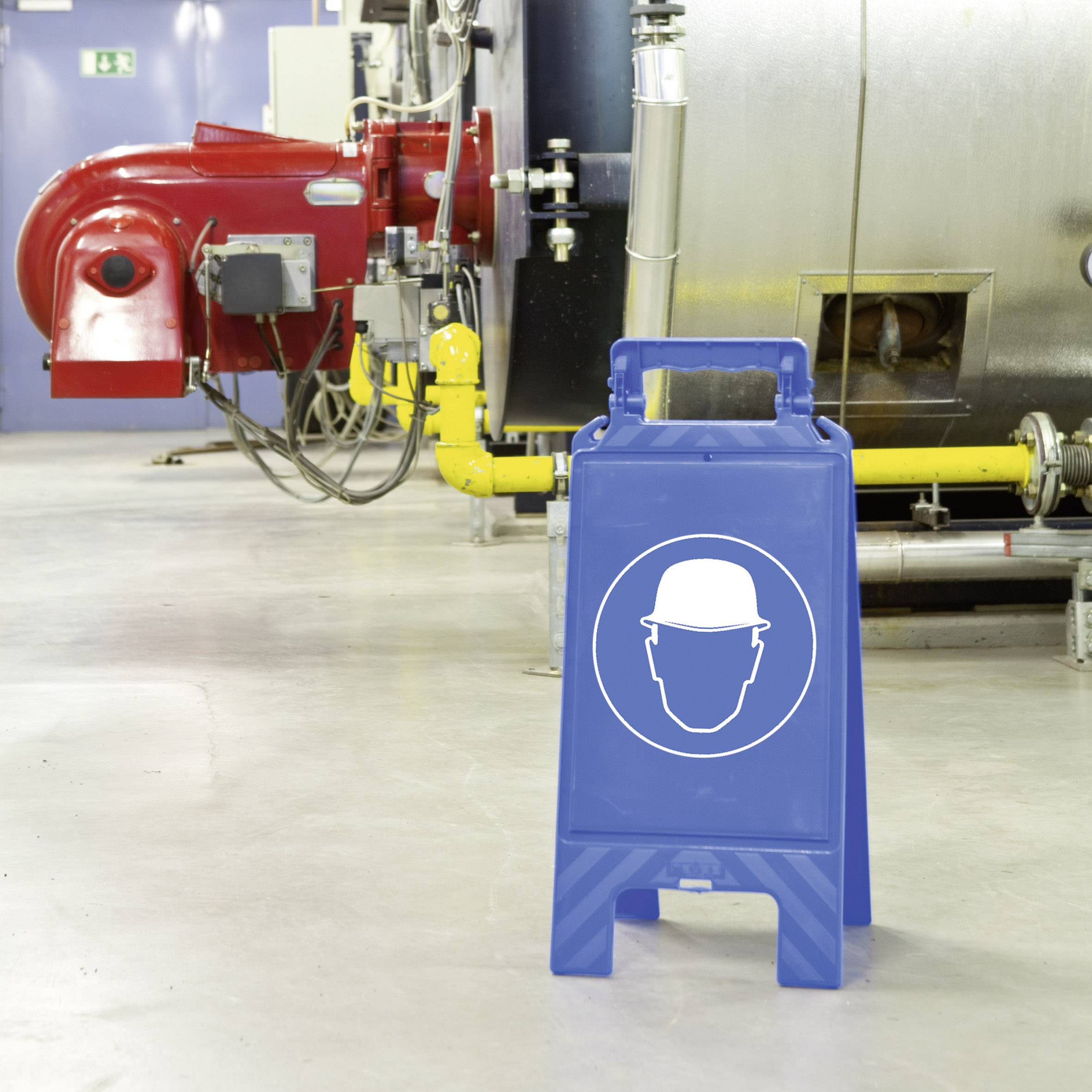 Warning sign in a factory shows a symbol for protective equipment in front of a large industrial boiler and pipelines.