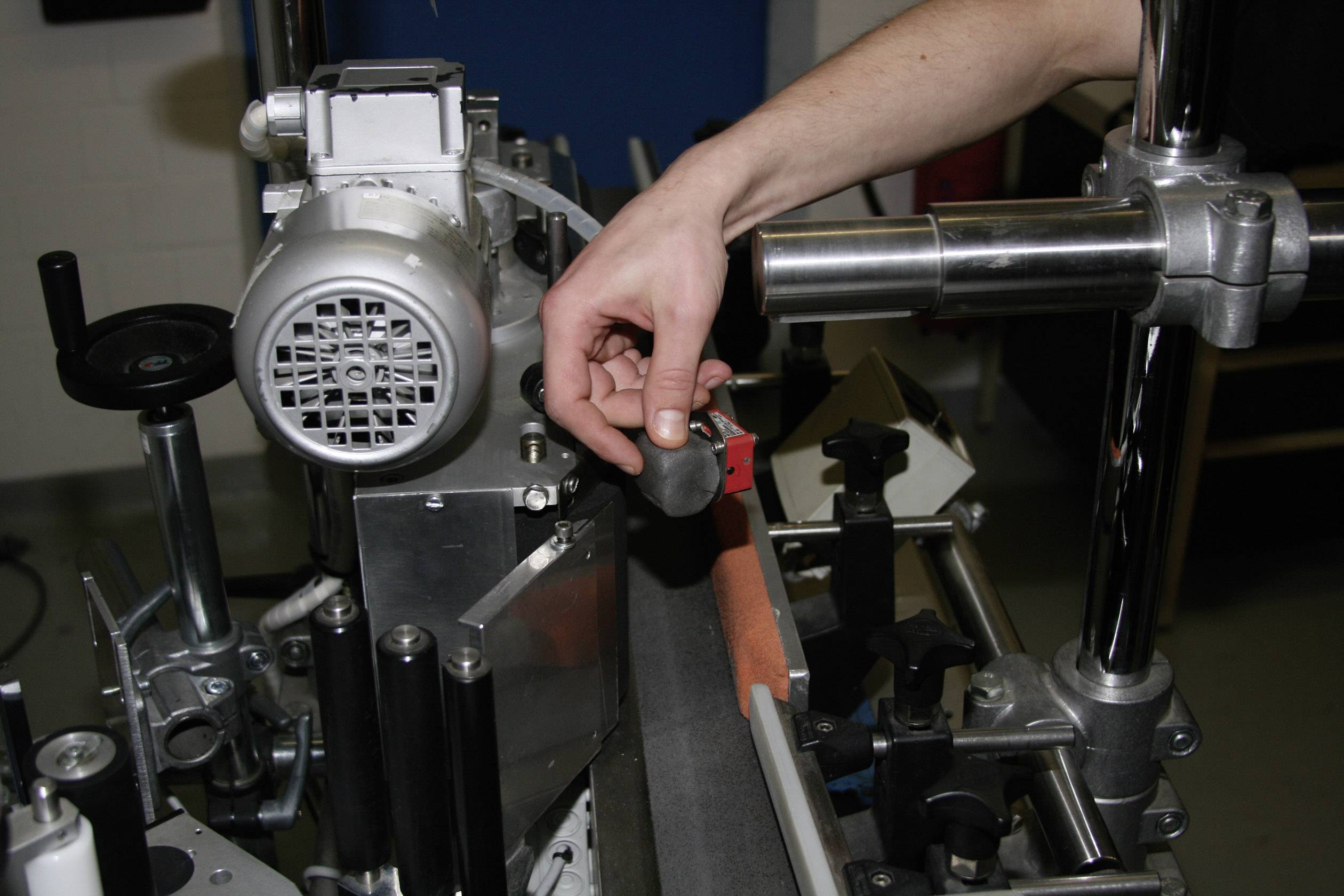 A person is adjusting an industrial machine with a spanner, likely for fine-tuning a mechanism.