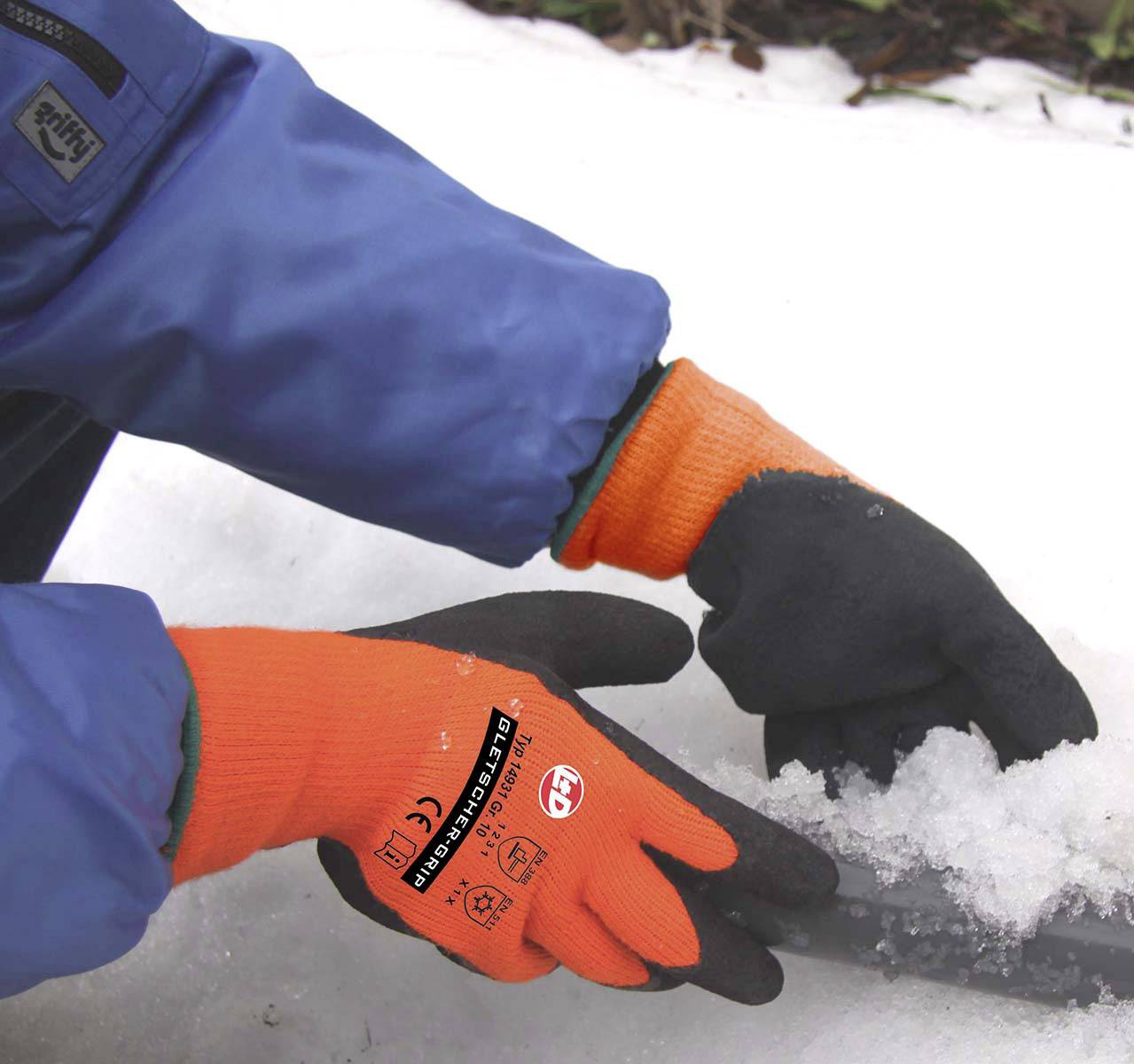 A person wearing orange gloves is shovelling snow with a small shovel. A blue item of clothing is visible.