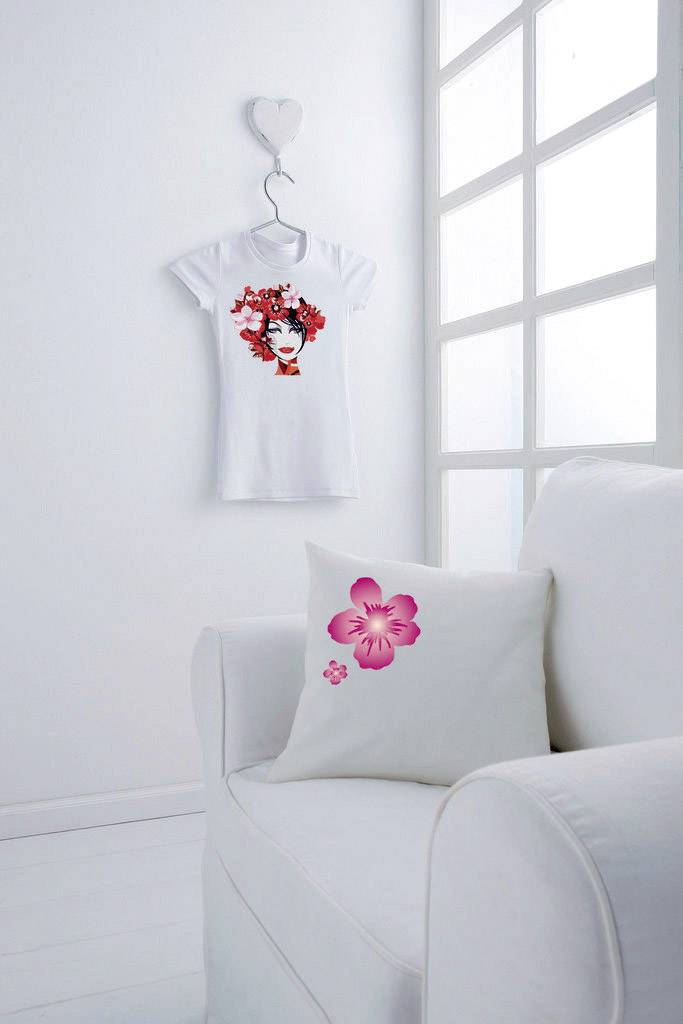 A white sofa with a cushion depicting pink flowers. On the wall hangs a white T-shirt featuring a woman's face and red flowers.