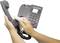 Someone is cleaning a grey telephone with a cloth while holding the receiver.