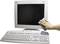 A hand wipes the screen of a desktop computer clean; a keyboard lies in front of it.