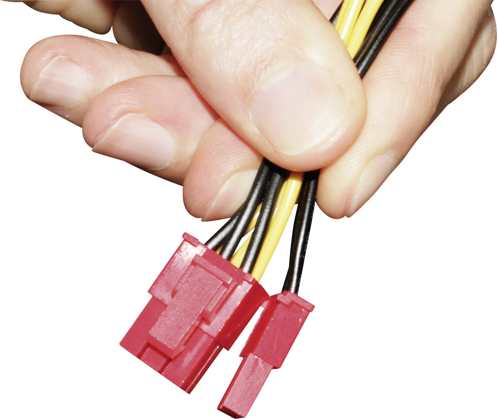 A hand is holding two red plastic plugs with accompanying black and yellow cables.