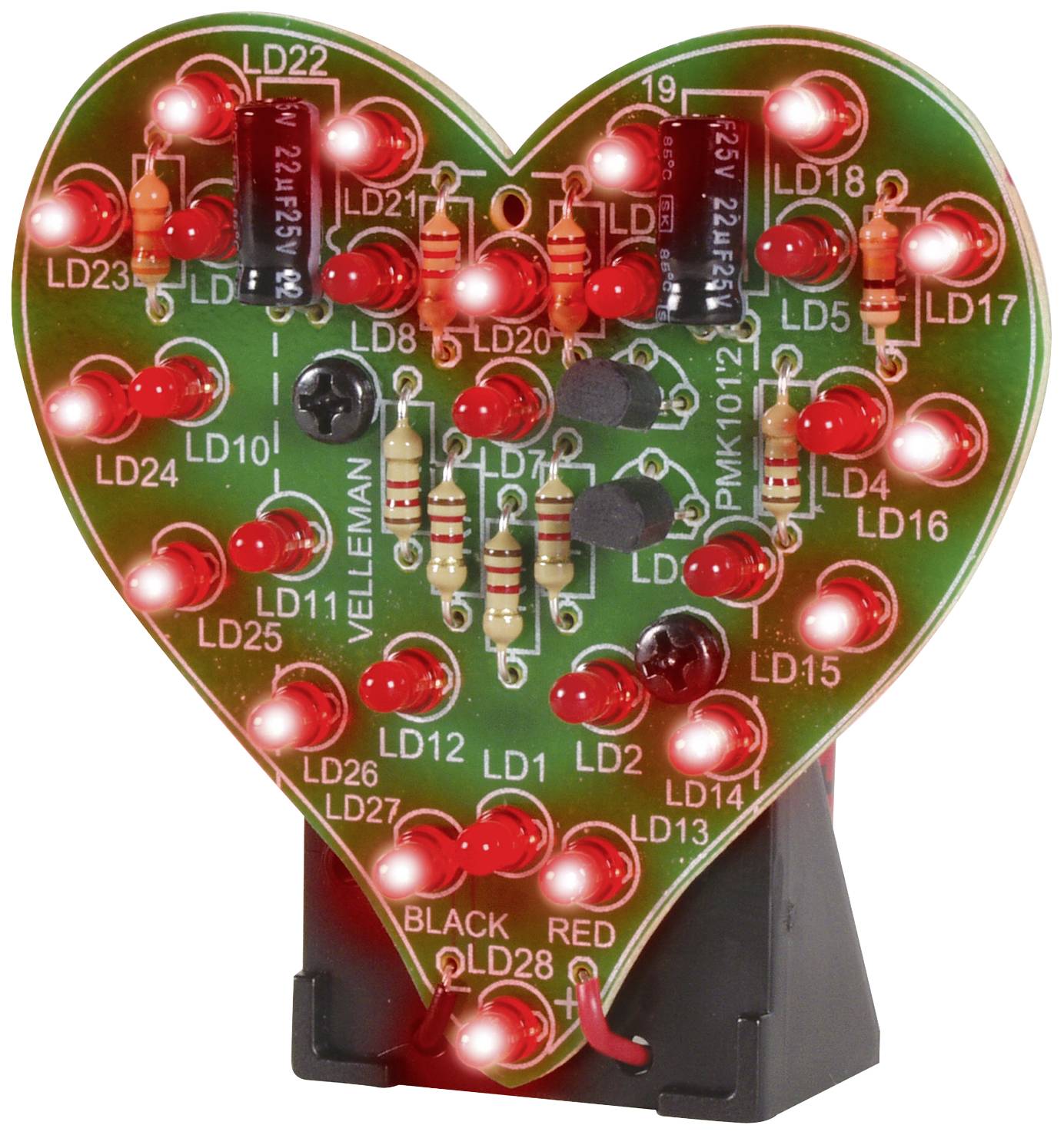Carte en forme de cœur avec des LED rouges lumineuses, des condensateurs et des résistances. Elle repose sur un socle noir.
