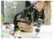 Un scientifique portant des lunettes de sécurité examine une lame sous un microscope dans un laboratoire. Un mètre numérique pour plantes se trouve au premier plan.
