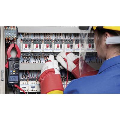 Une personne équipée d'un équipement de protection travaille sur un armoire électrique, mesurant des valeurs électriques avec un multimètre affichant 234,6.