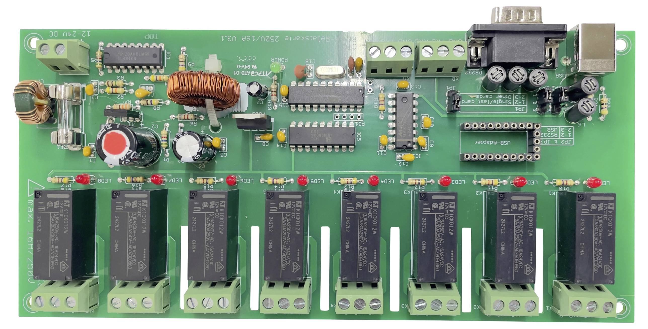 Circuit électronique avec plusieurs relais, condensateurs et circuits intégrés. À gauche une bobine, en haut des connecteurs enfichables, à droite une interface série.