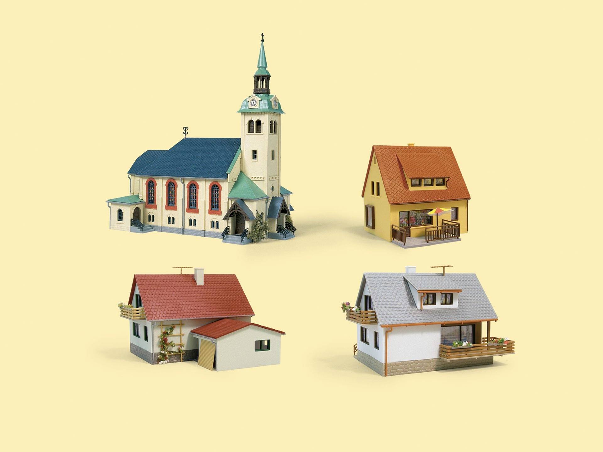 Quatre petites maisons et une église au toit bleu-vert posées sur un fond uni, mettant en évidence la diversité architecturale.