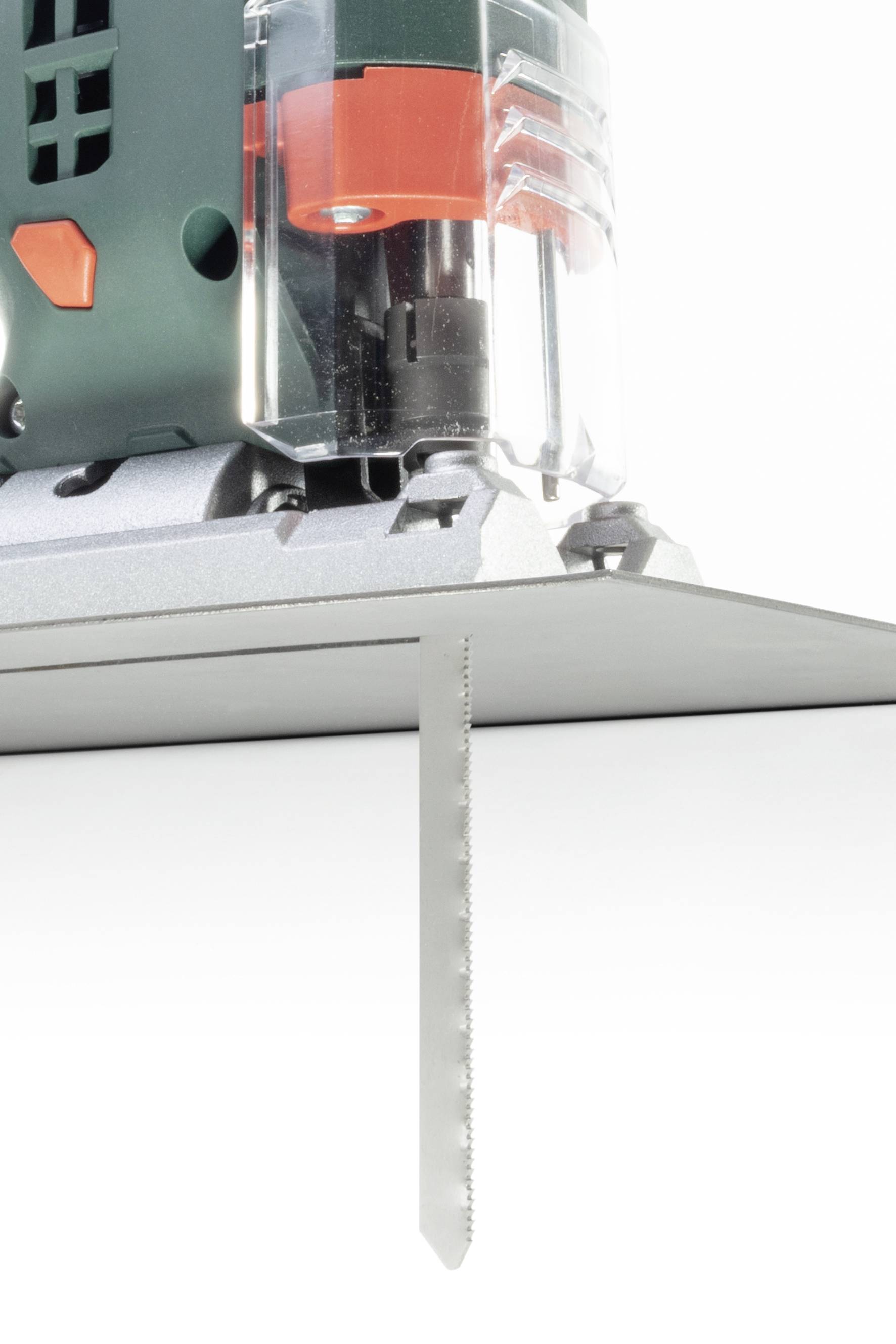 Gros plan d'une scie sauteuse électrique en train de scier une fine tôle métallique. Le mouvement de la scie est dirigé vers le bas.