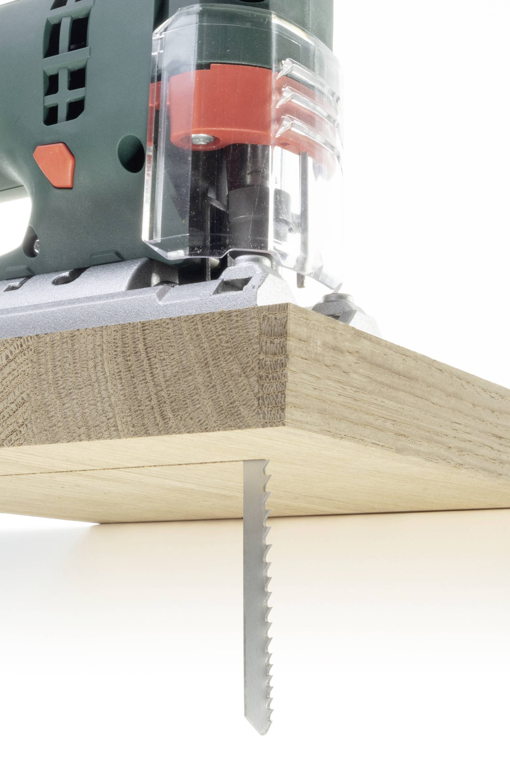 Scie sauteuse électrique coupe une planche de bois avec une lame de scie en gros plan, montrant une coupe précise.