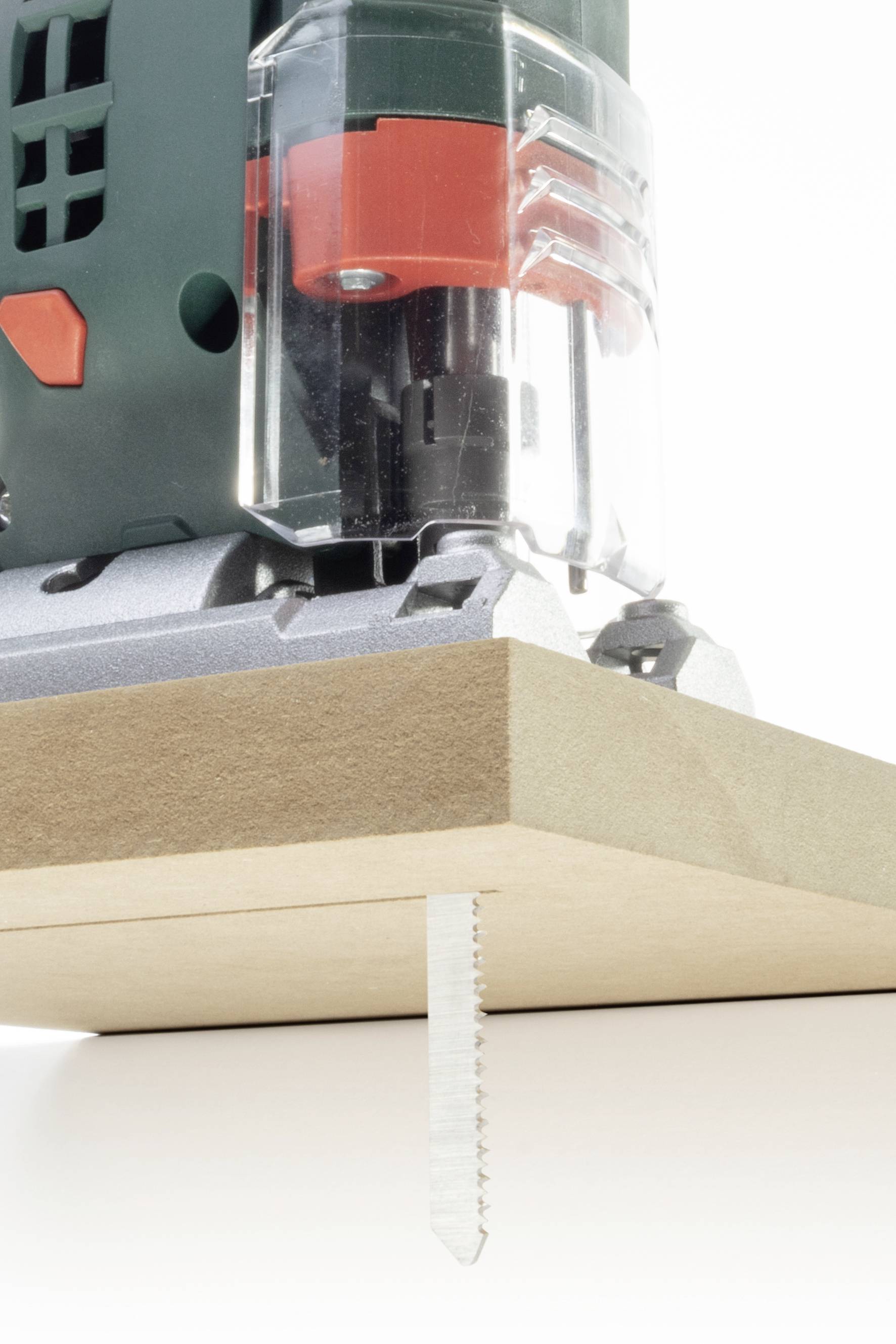 Une scie sauteuse coupe une planche en bois. La lame est visible sous la planche, tandis que la scie est montrée de près et en détail.