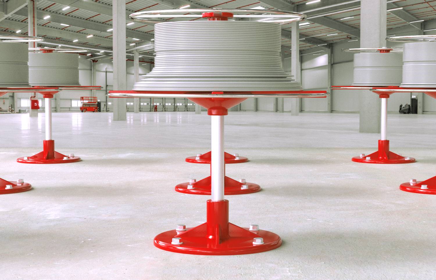 De grandes bobines de câbles industriels blancs sur des supports métalliques rouges à l'intérieur d'une zone de stockage d'entrepôt lumineux.
