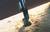 Une perceuse métallique fore un trou dans un morceau de bois, entourée de copeaux de bois.